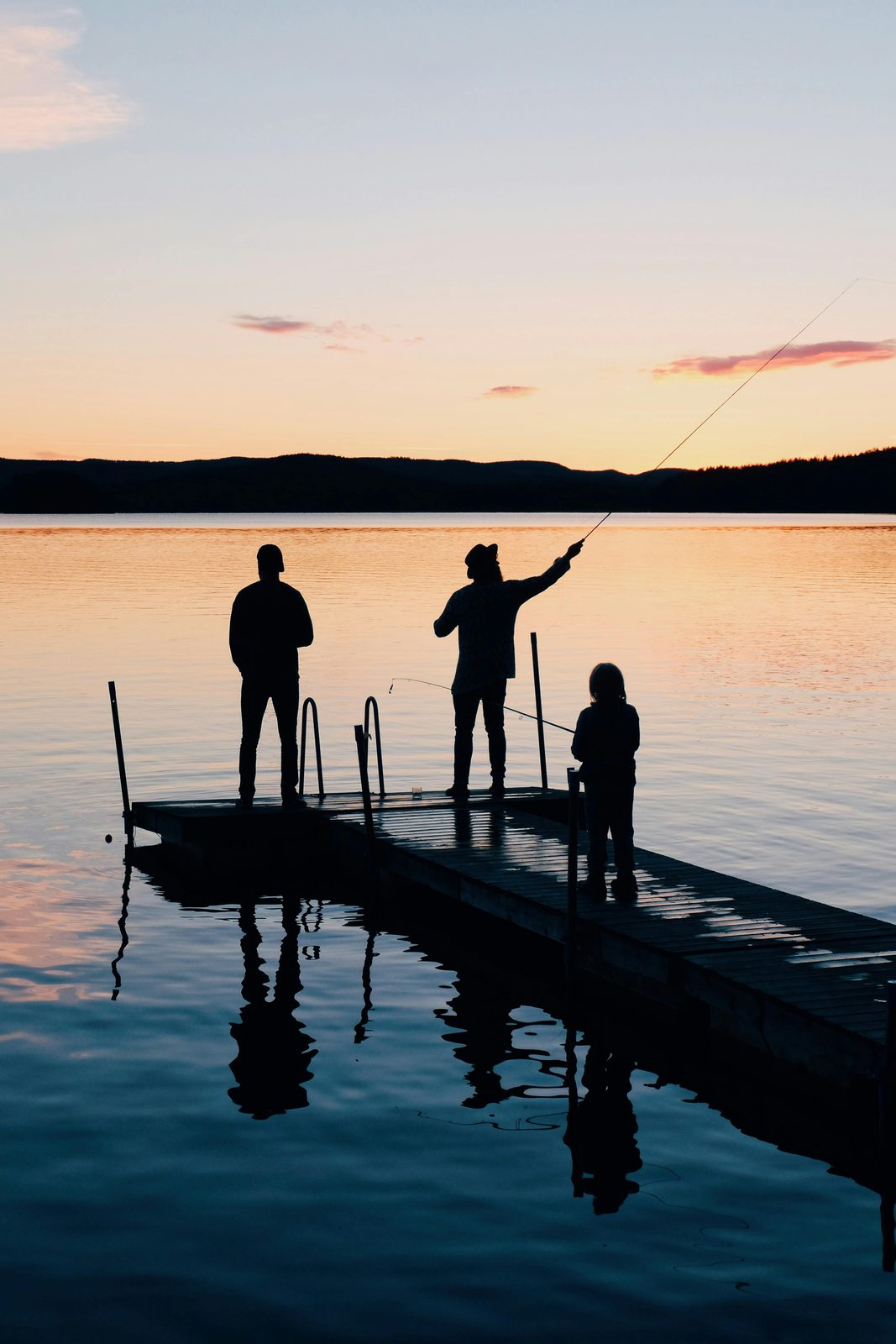 Family fishing from a dock at sunset